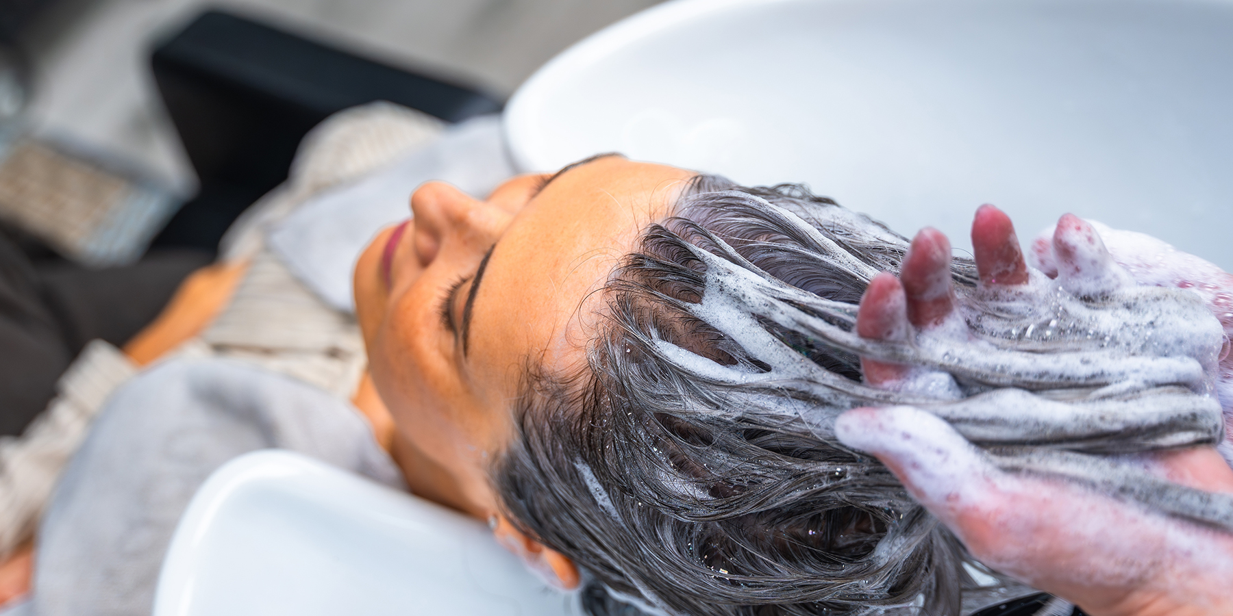 Mature,Woman,Relaxing,With,Eyes,Closed,As,A,Hairdresser,Shampoos