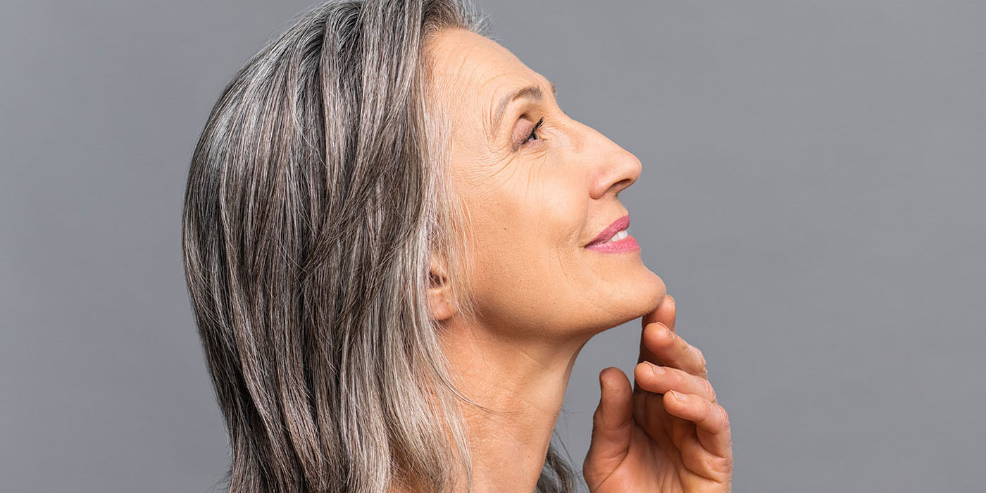 Bright,Mature,Lady,Standing,In,Profile,Looks,Up,,Touching,Gently
